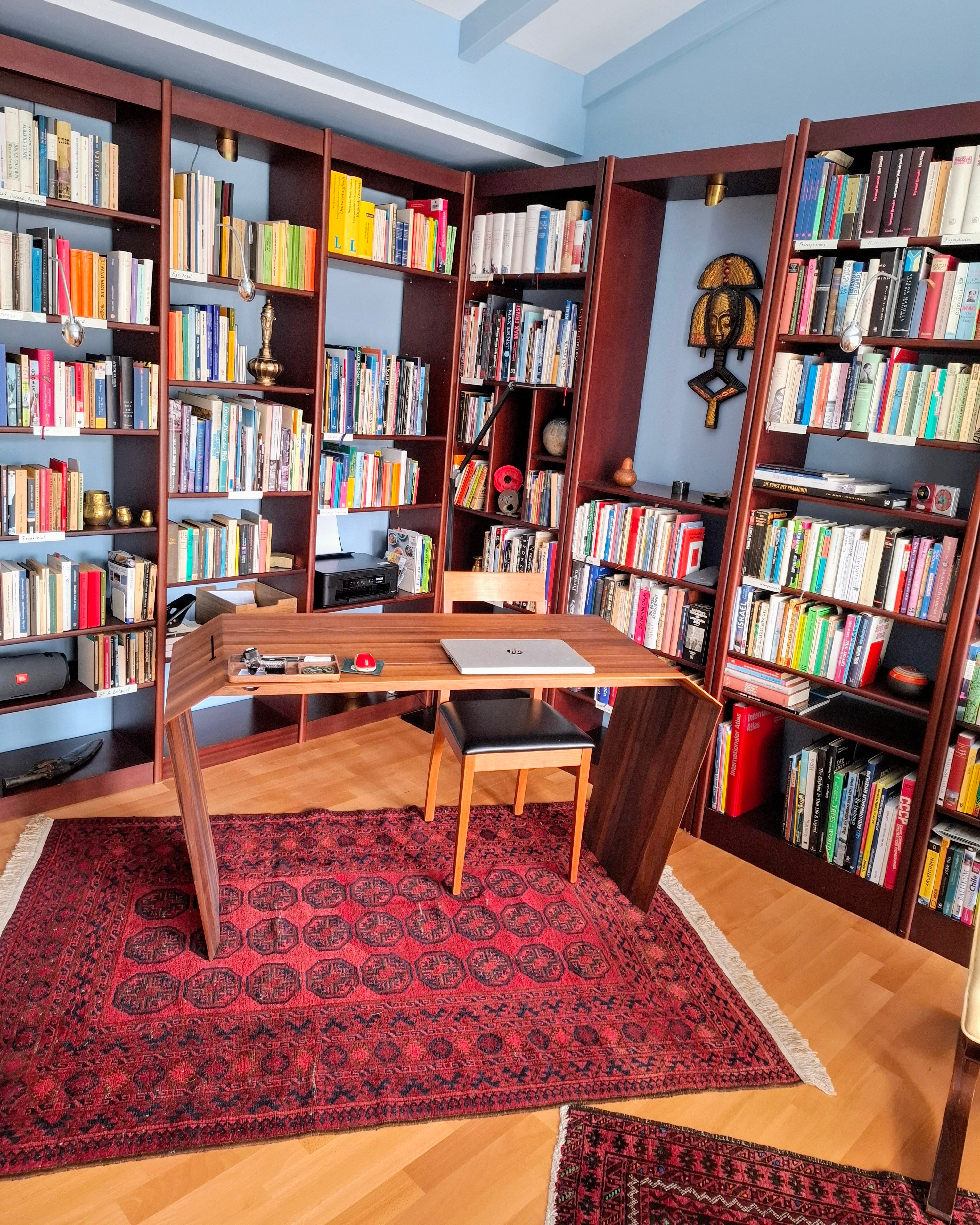 EDELHOLZ DeskPURE Schreibtisch in Nussbaum im Arbeitszimmer von Dr. Rolf Sülzer mit Bücherwand, Perserteppich und Holzstuhl