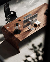 EDELHOLZ DeskPRO Schreibtisch in Deep Walnut, Vogelperspektive auf die Tischplatte mit Monitor, Tastatur, Tischleuchte und Bürostuhl [finish:deep-walnut]